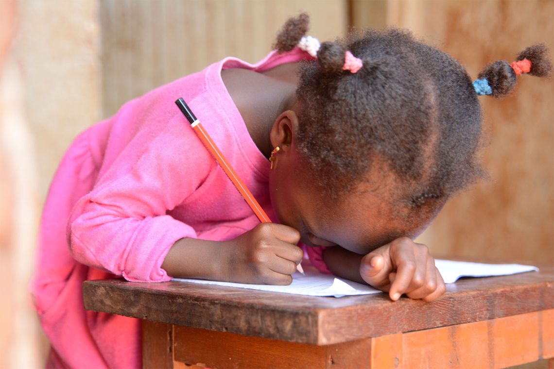 Afrikanisches Mädchen sehr dicht über ein Schulhelft gebeugt
