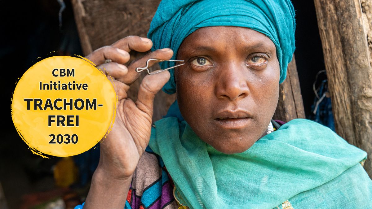 Eine Frau mit buntem Koptuch und geröteten Augen hält eine Pinzette an ihre Wimpern.