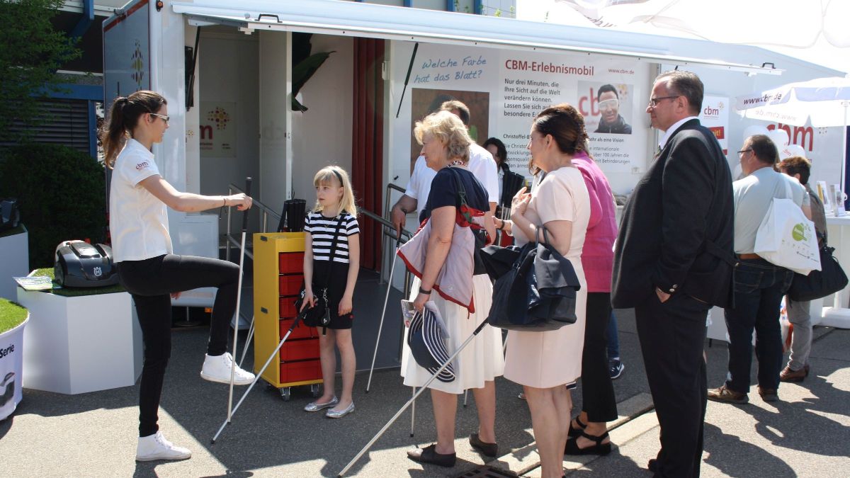 Menschen mit Taststöcken vor einem Anhänger