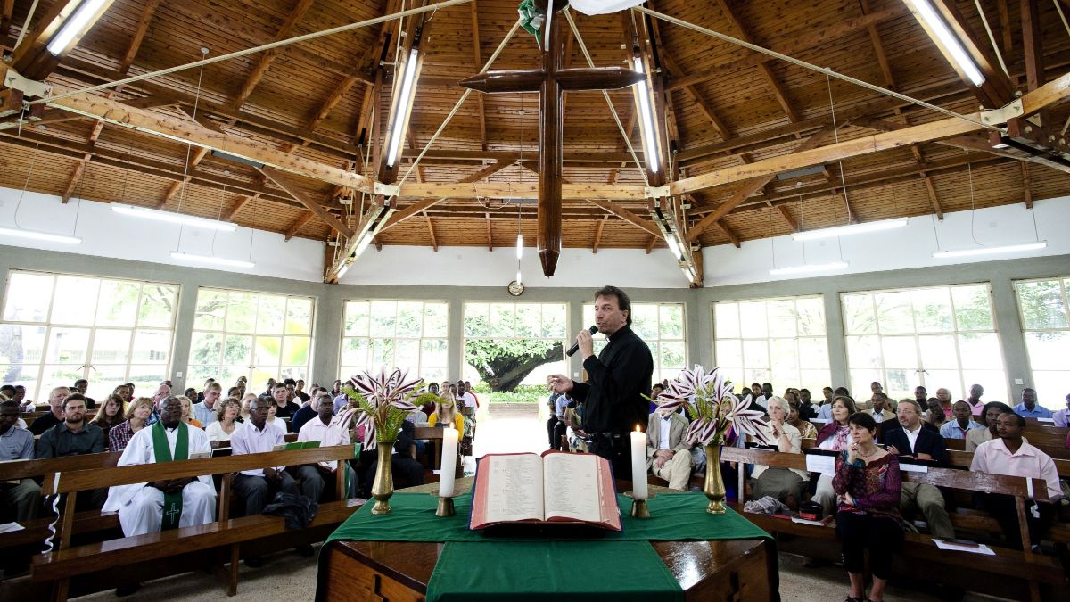 Ein Mann steht mit Mikrofon in einer Kirche hinter dem Altar. Finden Sie zahlreiche Ideen und Vorlagn für Ihren Gottesdienst.