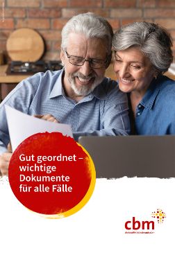 Eine ältere Frau und ein älterer Mann schauen gemeinsam auf ein Papier, das der Mann in den Händen hält.