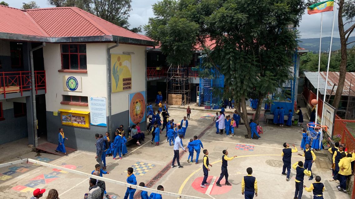Ein Schulgebäude mit spielenden Kinder davor