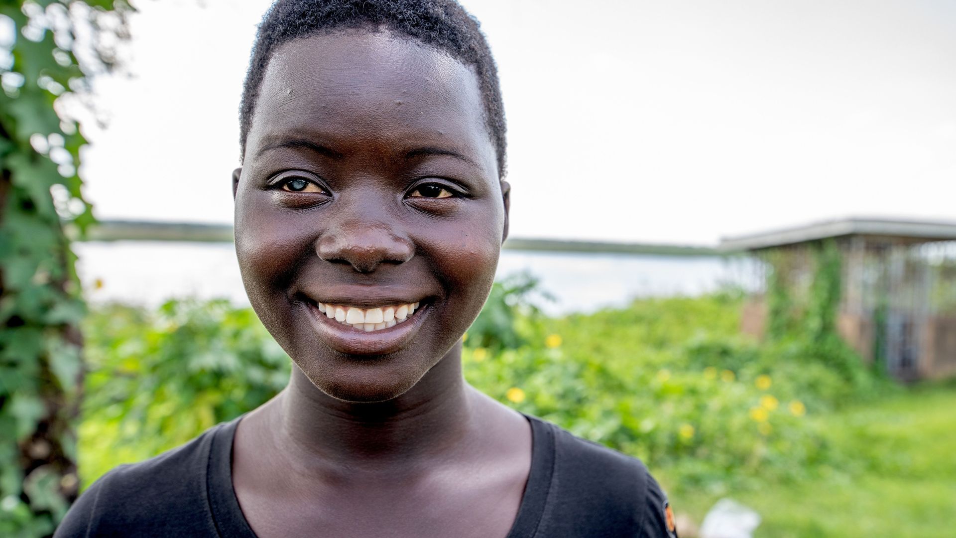Lachendes afrikanisches Teenager-Mädchen mit einer weißen Pupille.