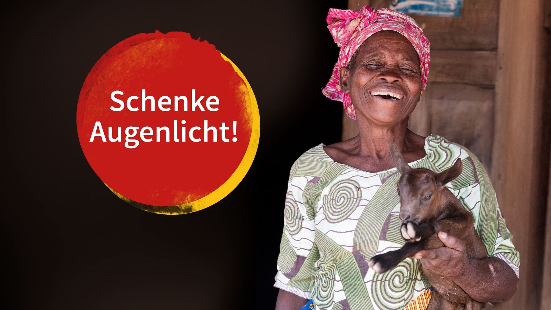 Lachende afrikanische Frau mit einer Ziege auf dem Arm.