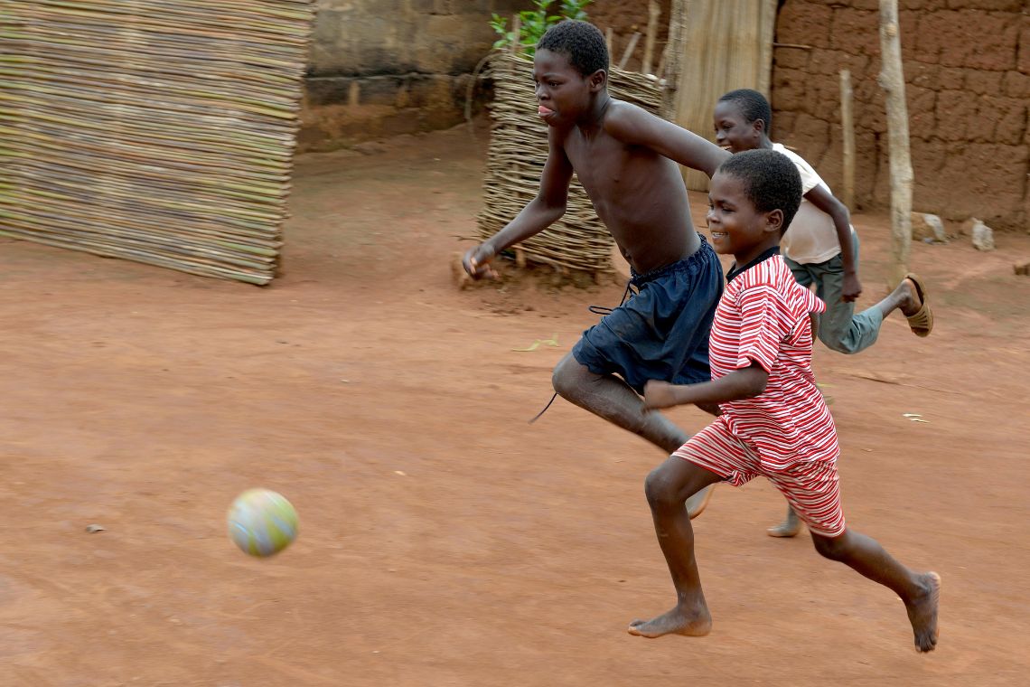 Zwei Jungen laufen hinter einem Ball her.