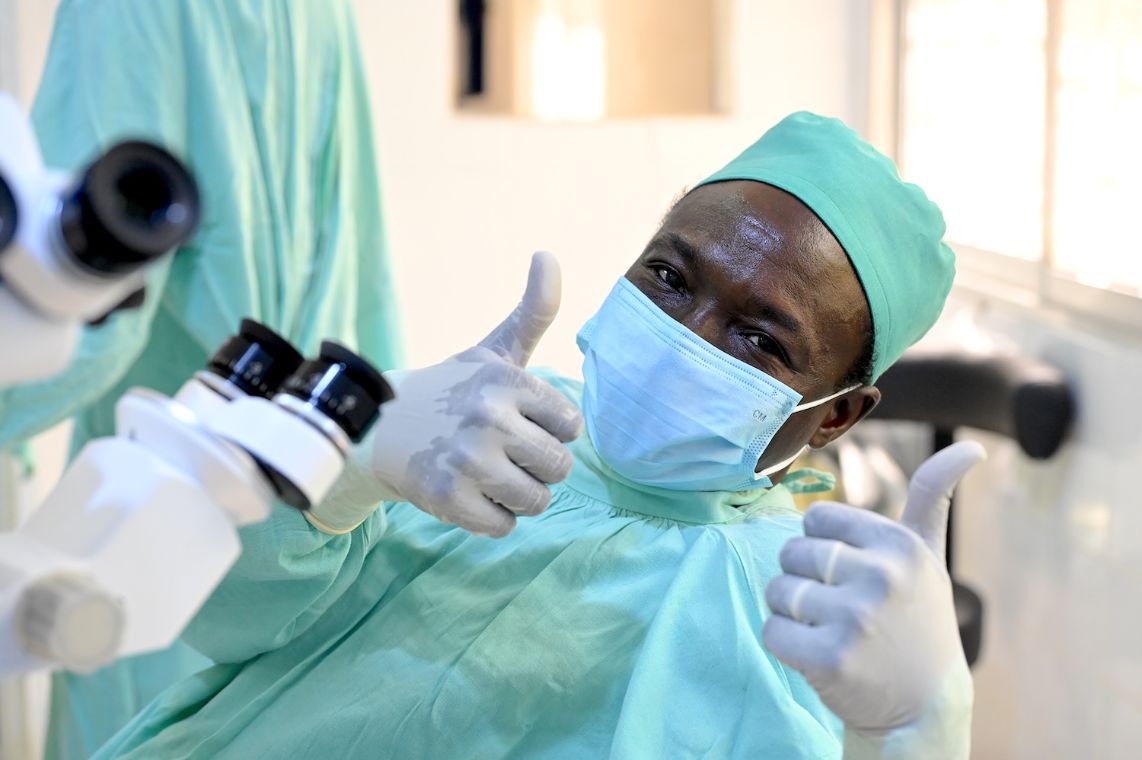 Ein Mann in OP-Kleidung lacht und hält beide Daumen hoch.