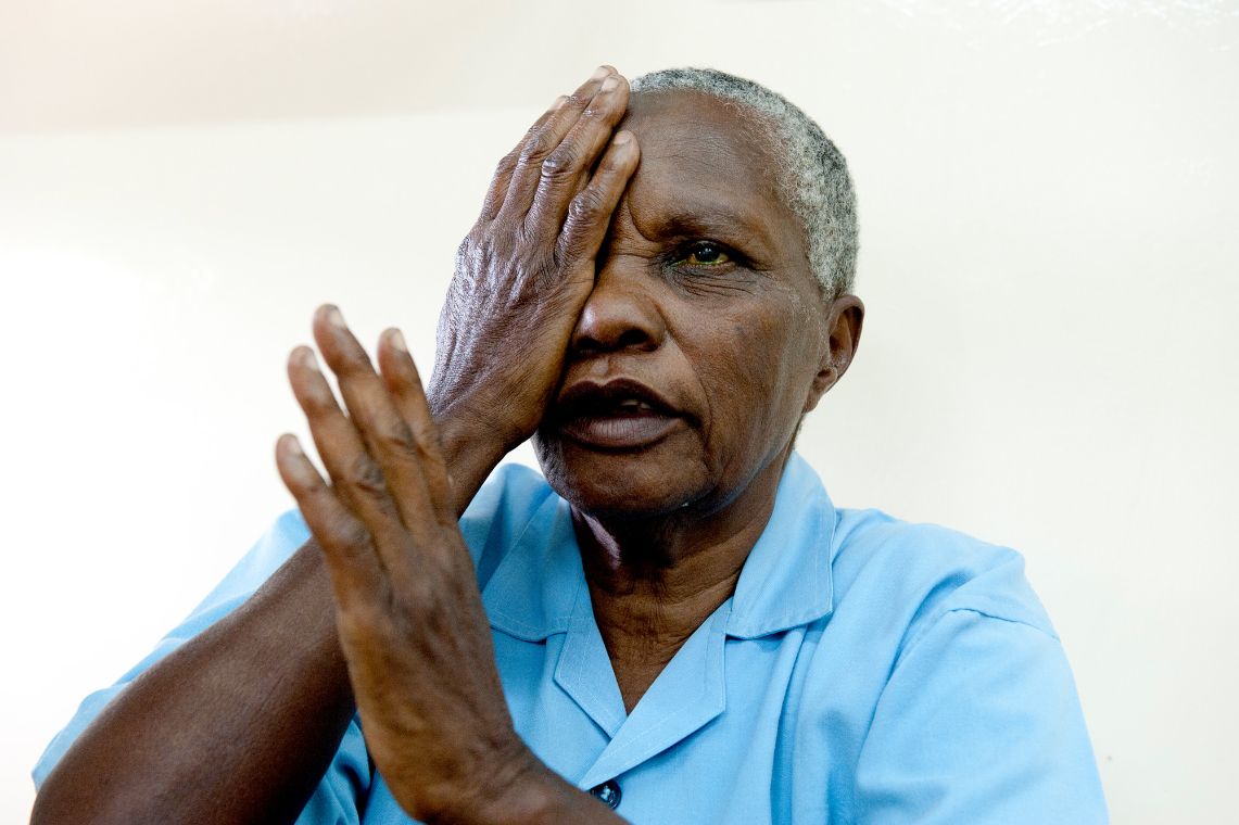 Ein blinder afrikanischer Mann hält sich sein rechtes Auge mit der Hand zu. 