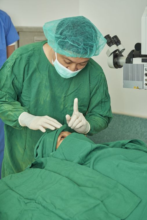 Ein Mann in OP-Kleidung spricht mit der Patientin auf dem OP-Tisch.