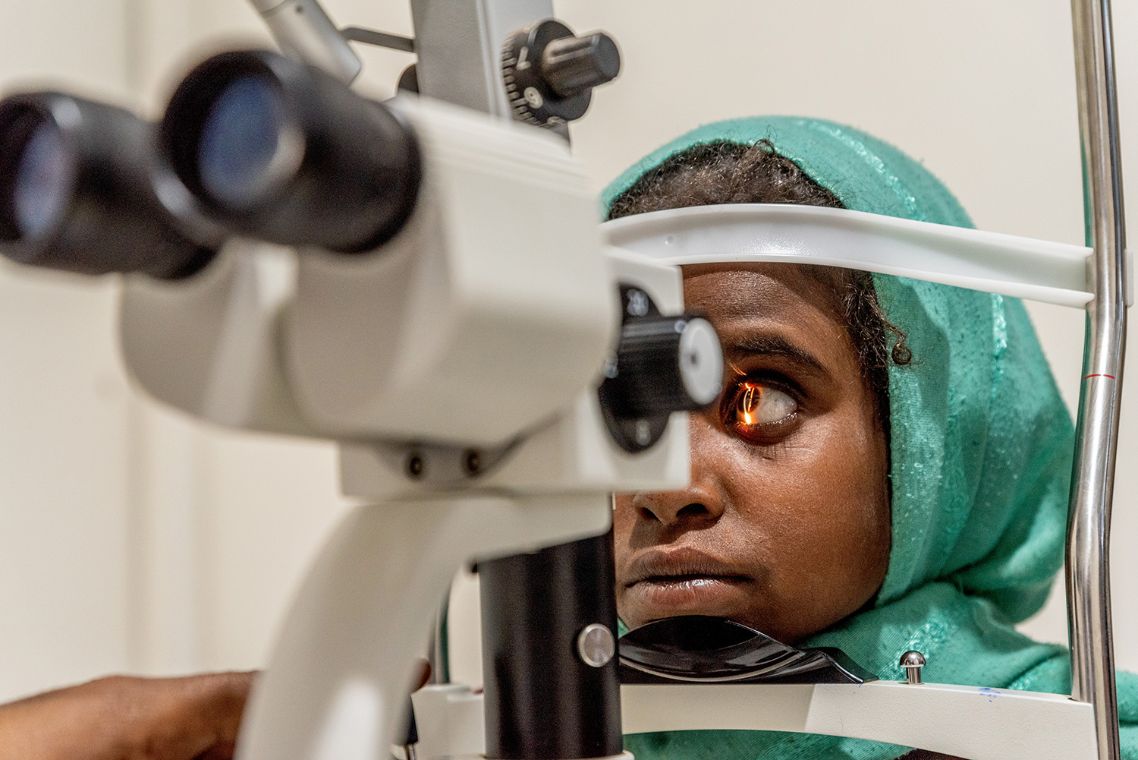 Ein etwa neunjähriges Mädchen legt den Kopf mit dem Kinn auf das Augenuntersuchungsgerät.
