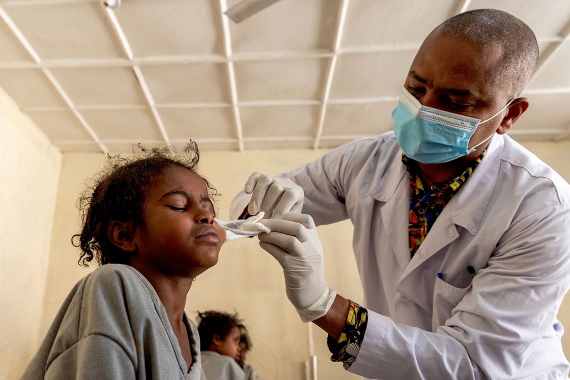Ein Mann entfernt den Augenverband eines etwa neunjährigen Mädchens.