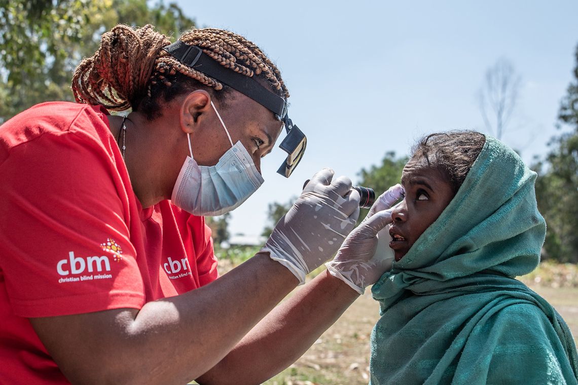 Eine Frau untersucht die Augen eines etwa neunjährigen Mädchens.