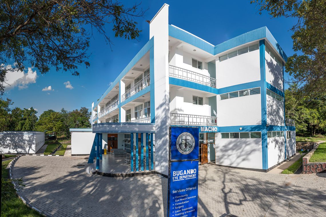 Dreigeschossiges weißes Gebäude mit leuchtend hellblau gestrichenen Geschosskanten im Sonnenschein mit strahlend blauem Himmel.