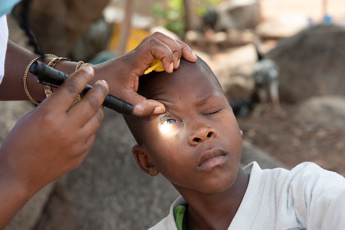 Ein Junge wird mit einer Lampe am Auge untersucht. 