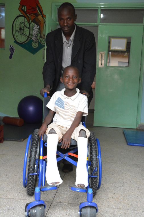 Ein Junge mit Gipsbeinen im Rollstuhl