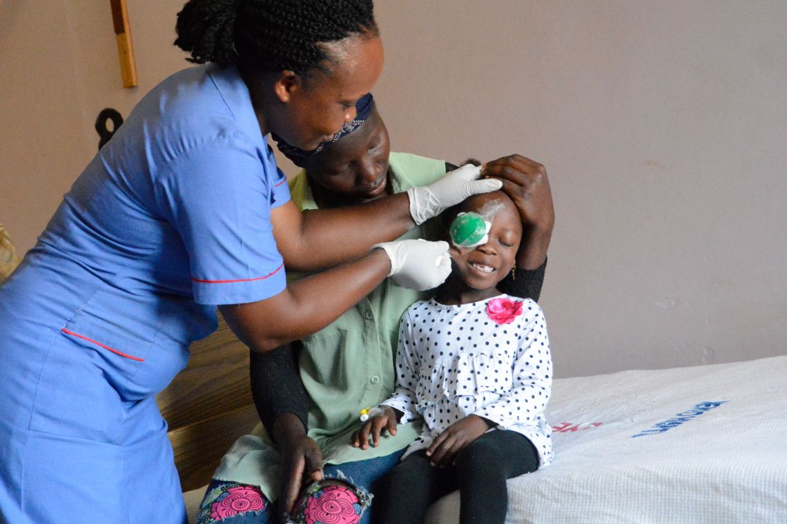 Krankenschwester entfernt einem Mädchen nach der Grauen-Star-Operation den Augenverband