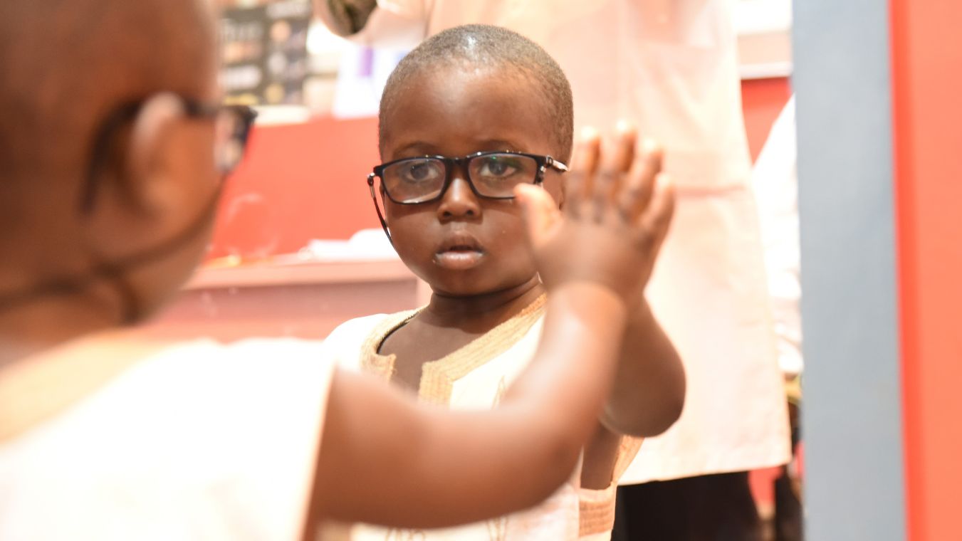 Afrikanischer Junge mit Brille schaut in den Spiegel