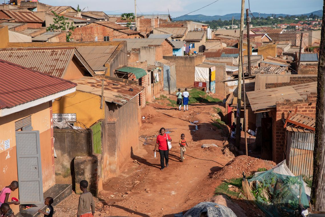 Aufnahme eines Armutsviertels in der ugandischen Hauptstadt Kampala. Abgebildet sind staubige Straßen und Wellblechhütten.