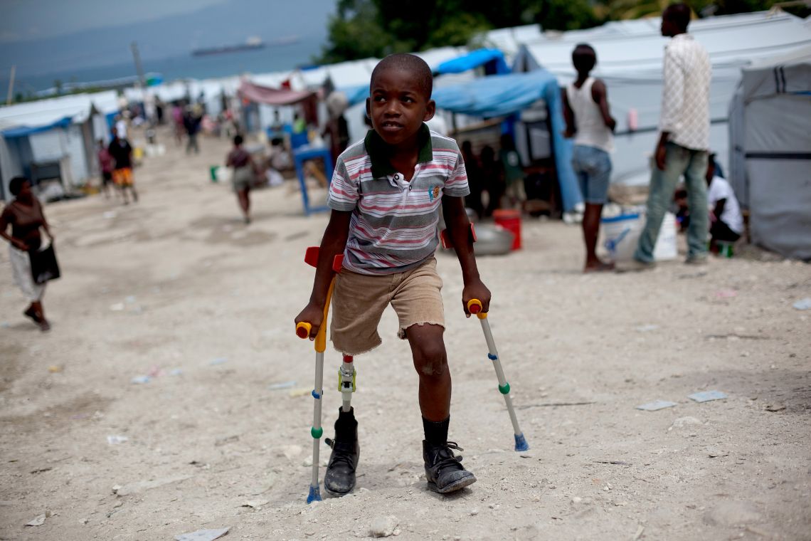 Ein kleiner Junge mit Beinprothese geht mit Krücken. Durch ein Erdbeben verlor er ein Bein.