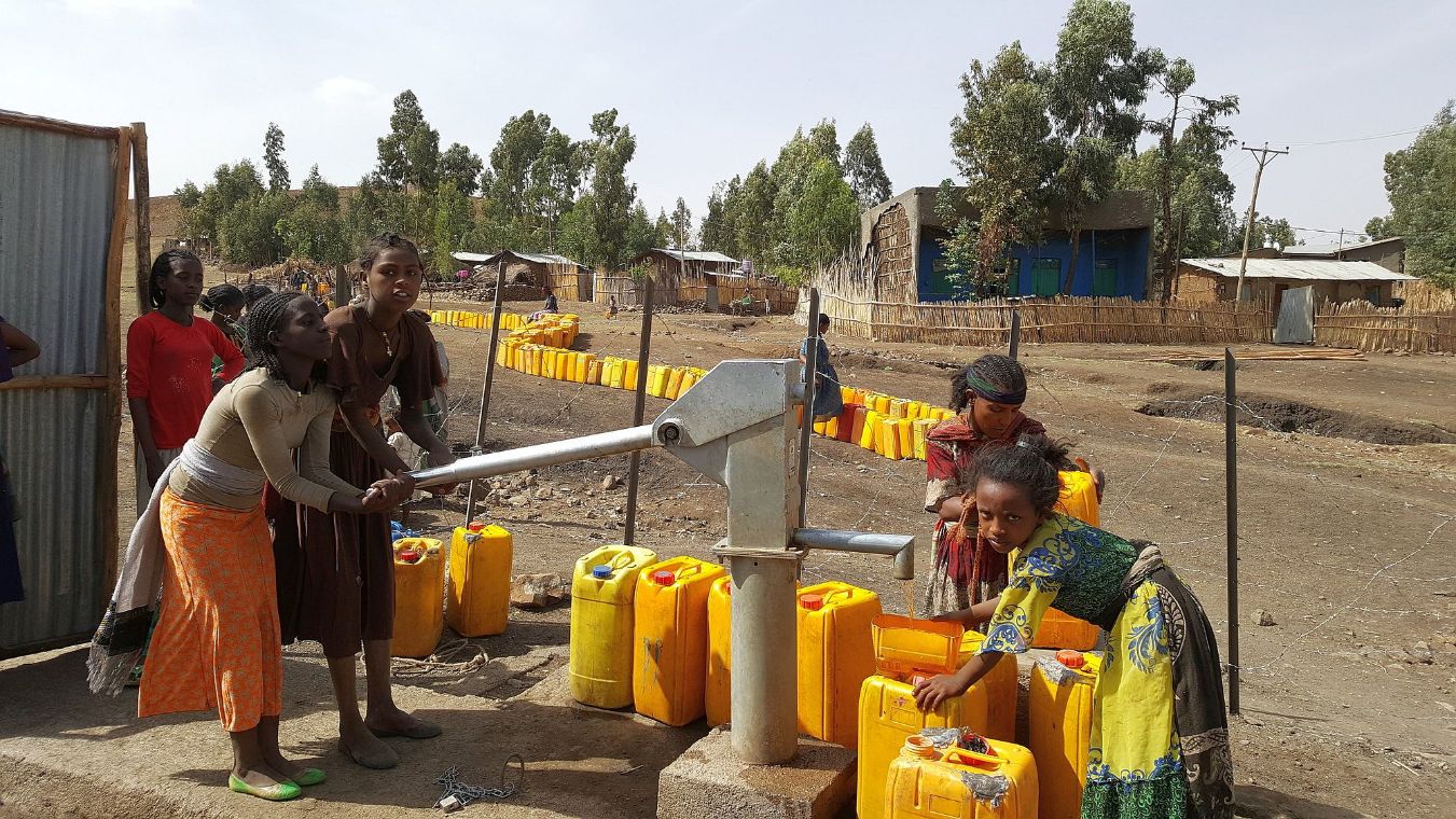 Kinder mit Wasserkanistern an einer Wasserpumpe