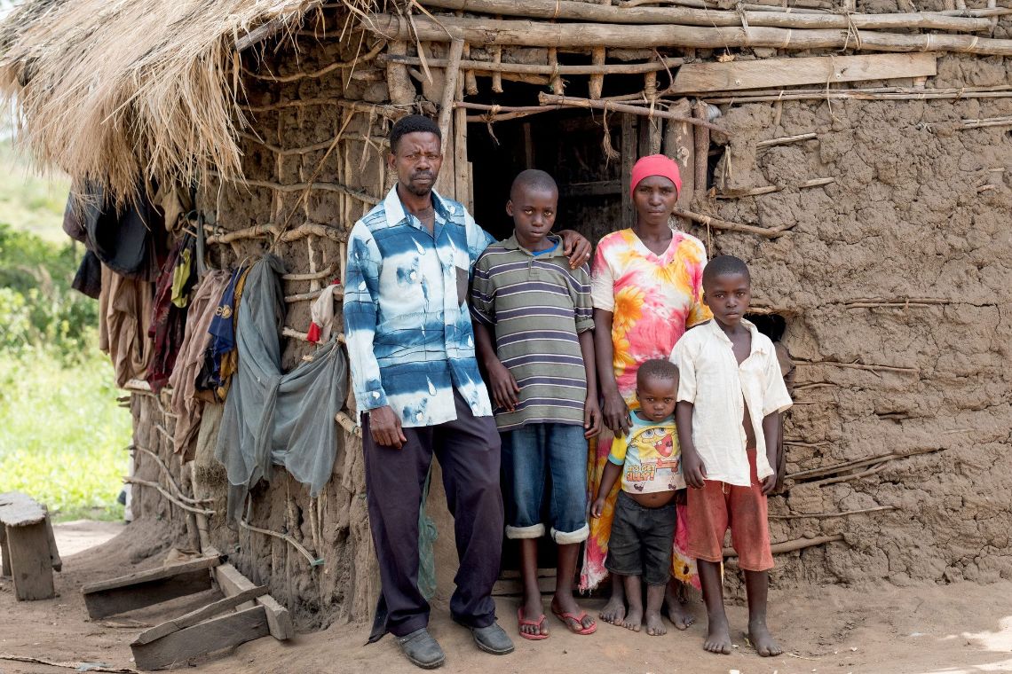 Eine afrikanische Familie steht vor ihrer Hütte.