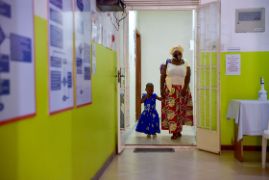 Afrikanische Frau mit Mund-Nasen-Schutz mit einem kleinen Mädchen an der Hand