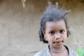 Afrikanisches Mädchen vor einer Lehmwand