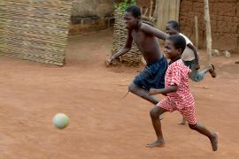 Zwei Jungen laufen hinter einem Ball her.