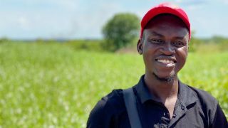 Zwei junge lachende afrikanische Männer, im Hintergrund ein Feld
