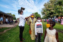 Drei junge lachende afrikanische Männer, im Hintergrund ein Feld