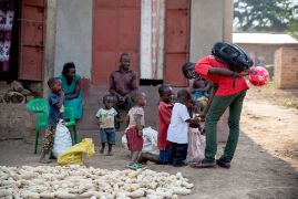 Drei junge lachende afrikanische Männer, im Hintergrund ein Feld