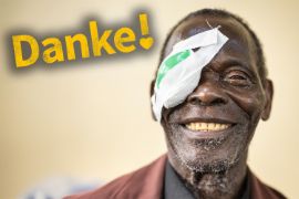 Älterer lachender Mann mit Augenverband.