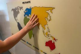 Die Weltkarte zum abtasten. Eine Hand fühlt über die Abbildung.