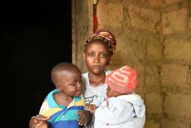 Junge afrikanische Frau mit zwei kleinen Kindern vor einer Mauer