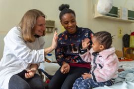 Deutsche Augenärztin und kleines tansanisches Mädchen geben sich high five