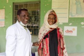 Äthiopische Frau steht lächelnd nebem einem Arzt