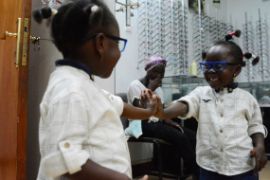 Afrikanisches Mädchen sieht sich nach der Operation am Grauen Star im Spiegel
