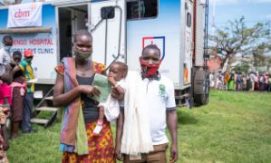 Menschen stehen vor einer mobilen Klinik in einem ungadischen Dorf