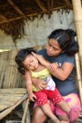 Philippinische Mutter hält ihre kleine Tochter auf dem Schoß.