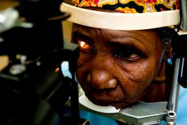 Eine ältere afrikanische Frau bekommt eine Augenuntersuchung. 