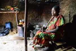 Eine ältere blinde afrikanische Frau sitzt allein in ihrer Hütte.