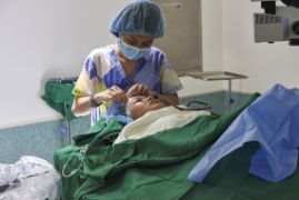 Eine Frau in OP-Kleidung nimmt einer Patientin die OP-Haube ab.