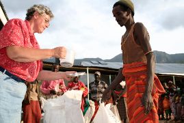 Eine Frau schöpft mit einem Becher aus einem Sack mit Reis oder Getreide, vor ihr steht ein Mann. Eine Dürre hatte zur Hungersnot in Kenia geführt.