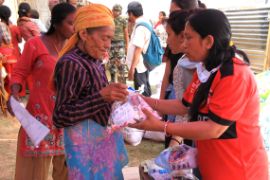 Eine CBM-Helferin verteilt in einem Camp Hilfsgüter nach dem Erdbeben von 2015.