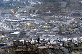 Zerstörung durch Erdbeben: Zelte, Häuser, eingestürzte Häuser nach heftigen Erdstößen in grauer, vegetationsloser Landschaft