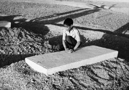 Ein Kind ertastet die eingravierte Schrift einer Grabplatte