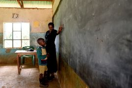 Eine afrikanische Frau und ein kleiner afrikanischer Junge an einer Tafel in einem Klassenzimmer