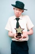 Junge mit Albinismus in Schuluniform trägt einen Stern in den Händen.