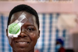 Lachendes afrikanisches Teenager-Mädchen mit Augenverband