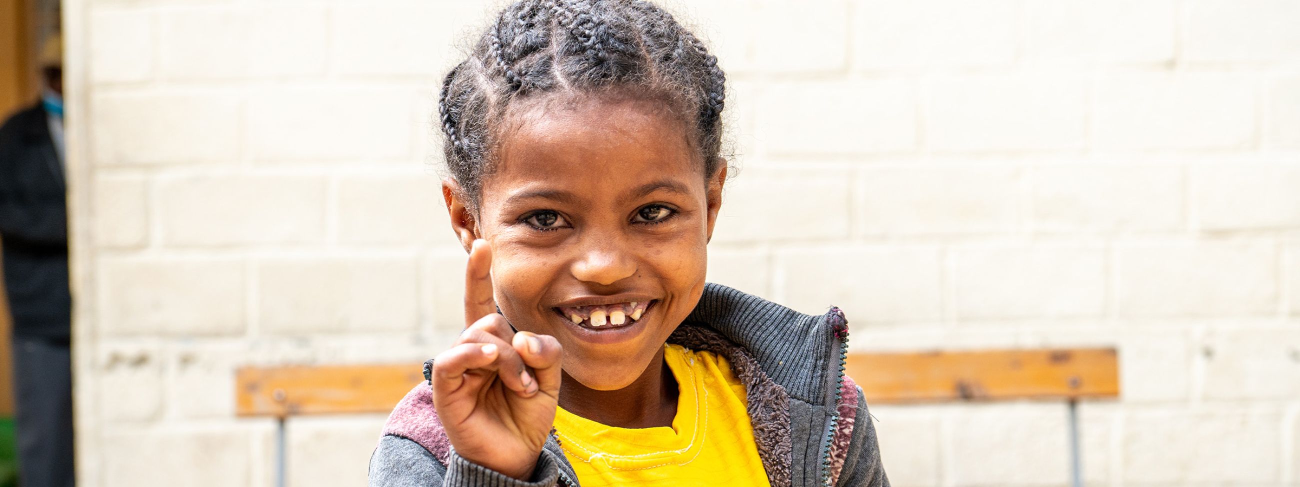 Ein etwa neunjähriges Mädchen steckt lachend den Zeigefinger hoch.