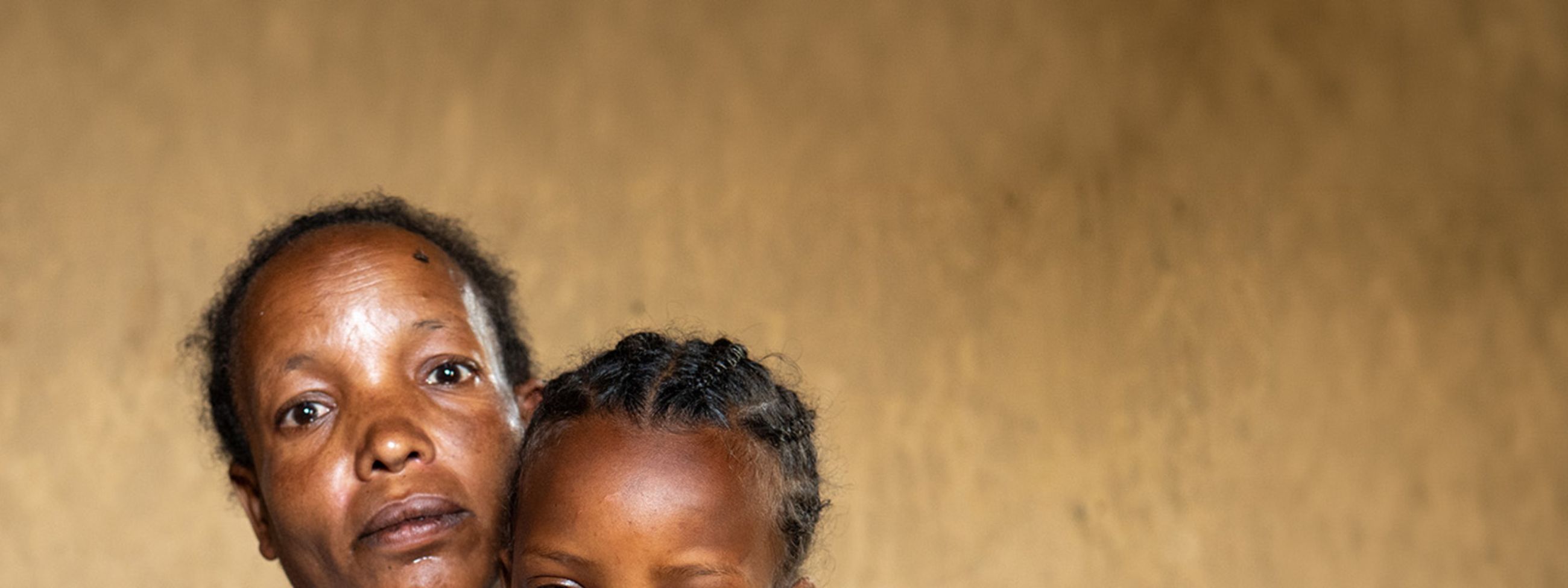 Eine Frau legt die Arme um ein etwa fünfjähriges Mädchen.